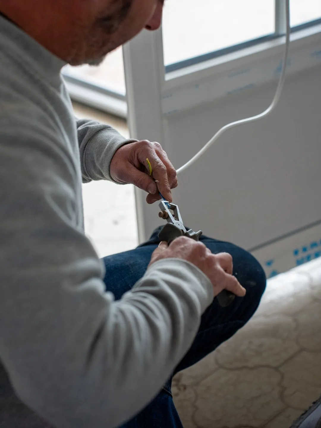 Technicien raccordant le câblage électrique d'un moteur de volet roulant dans un coffre