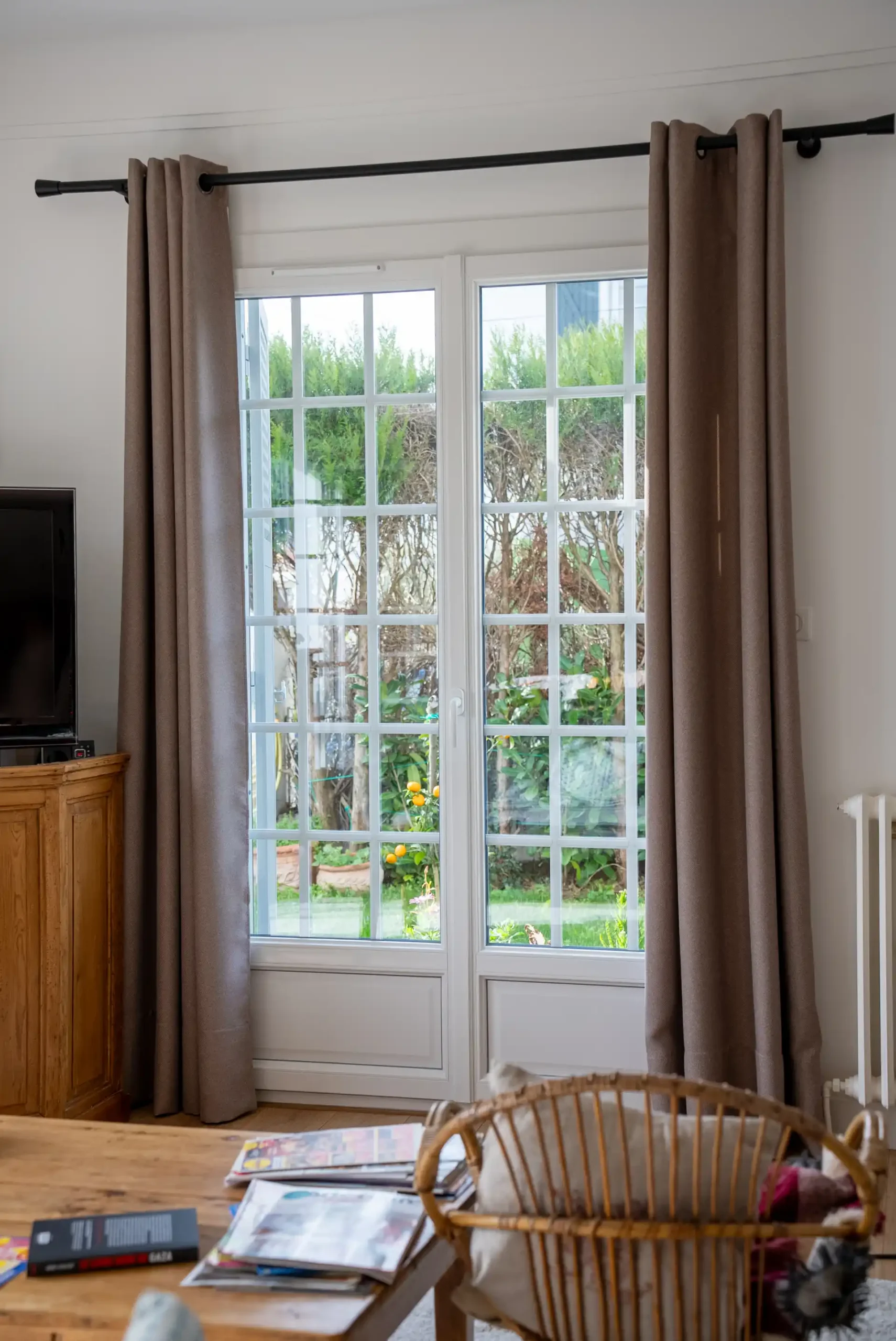 Porte-fenêtre PVC à petits carreaux dans un salon lumineux après rénovation