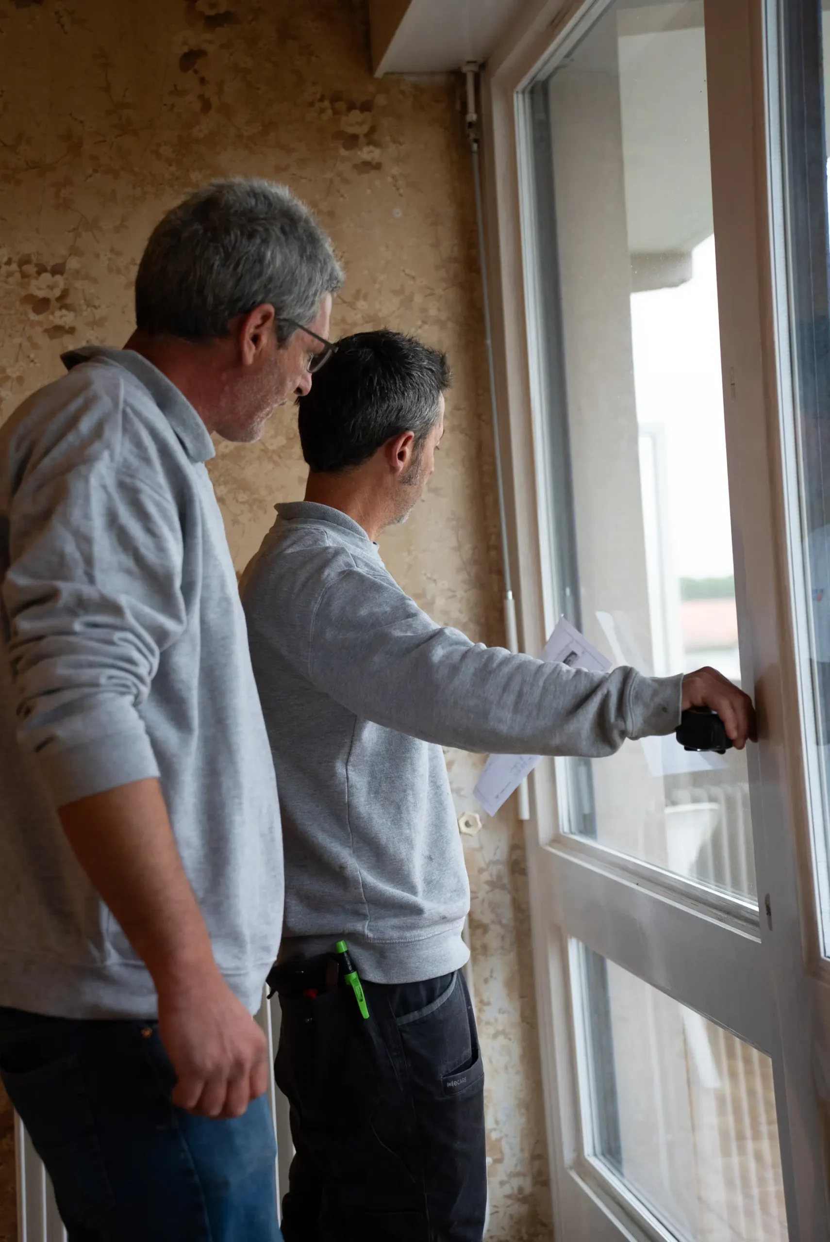 Menuisiers Adour PVC vérifiant la pose d'une fenêtre PVC blanche dans un appartement au Pays Basque