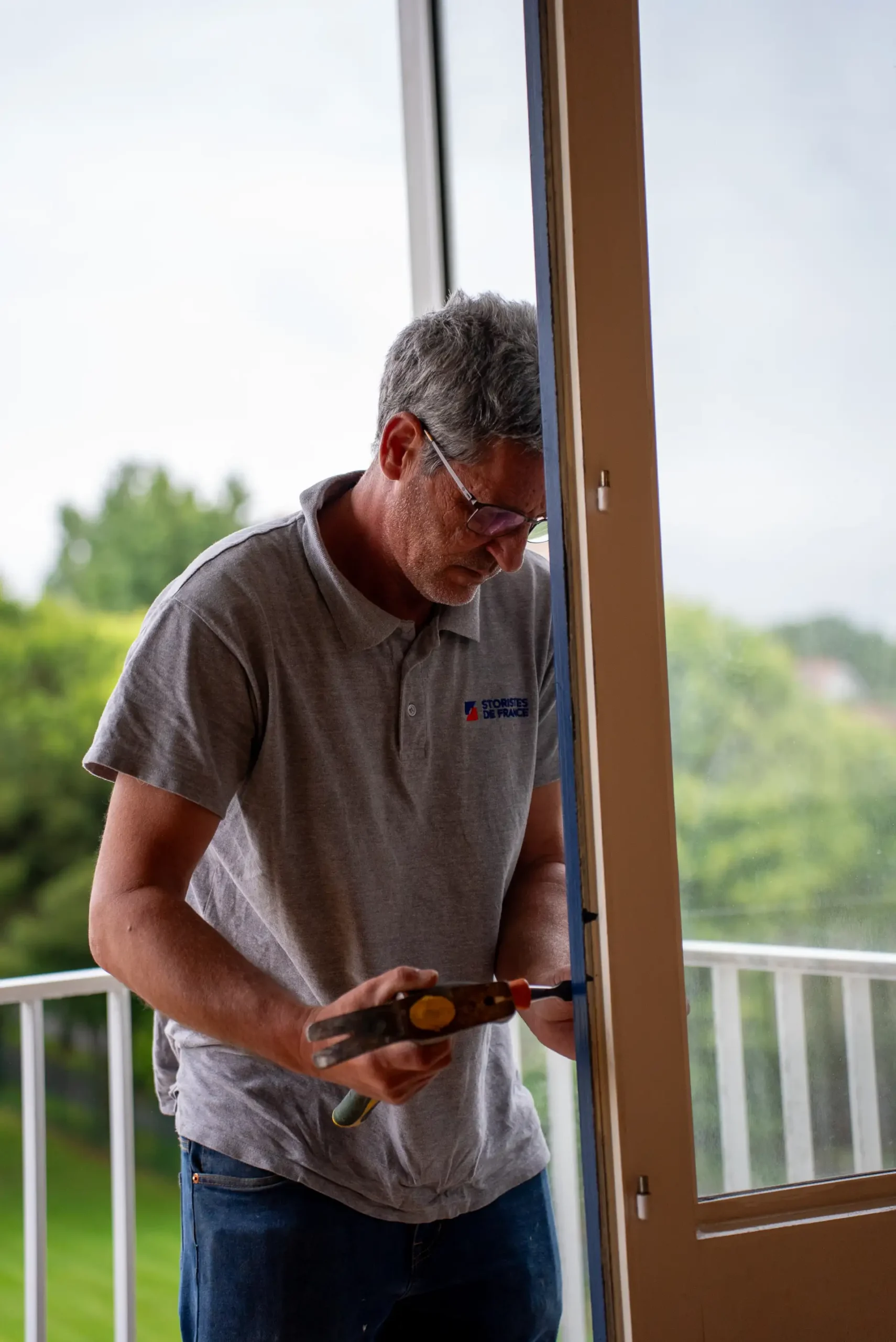 Technicien vérifiant le mécanisme de verrouillage d'une porte-fenêtre PVC après réparation