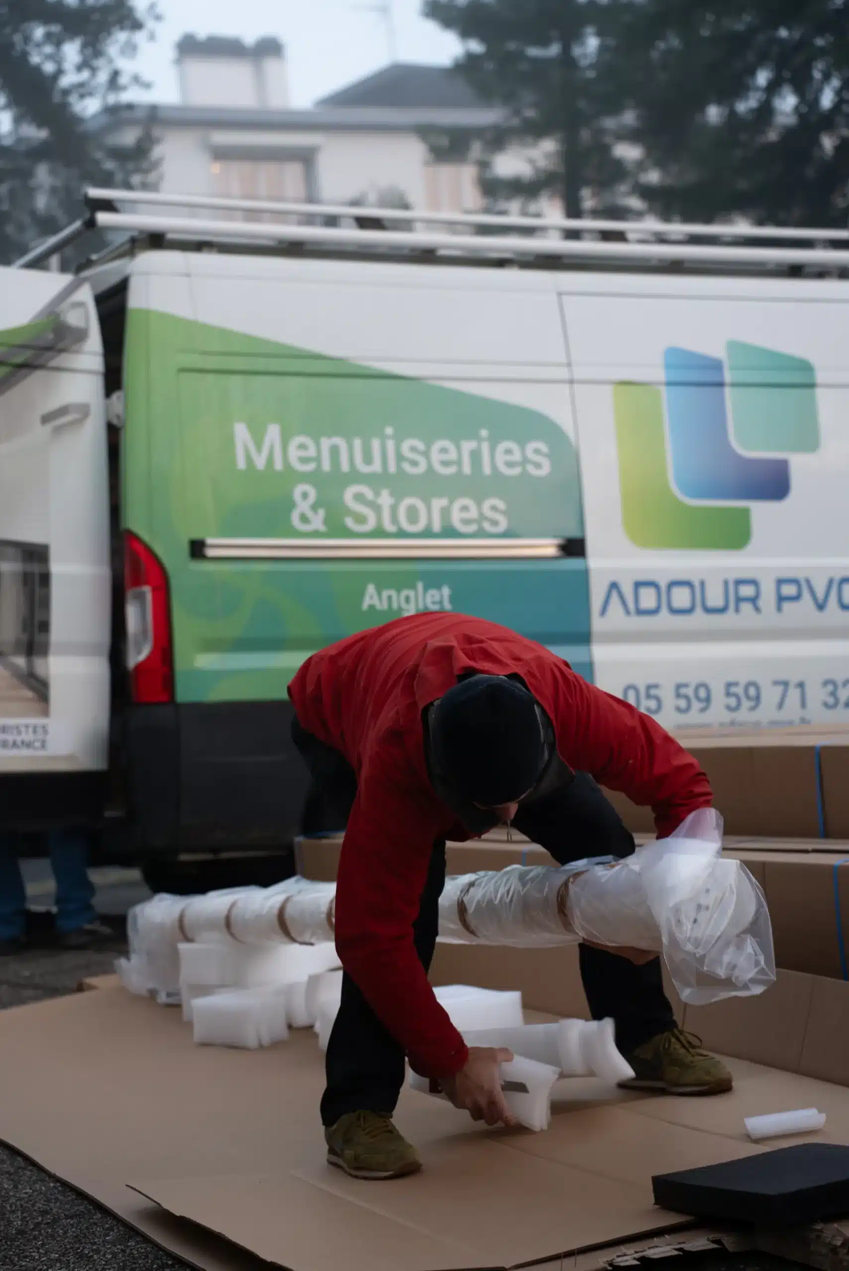 Artisan déballant des menuiseries devant le camion Adour PVC Menuiseries et Stores à Anglet