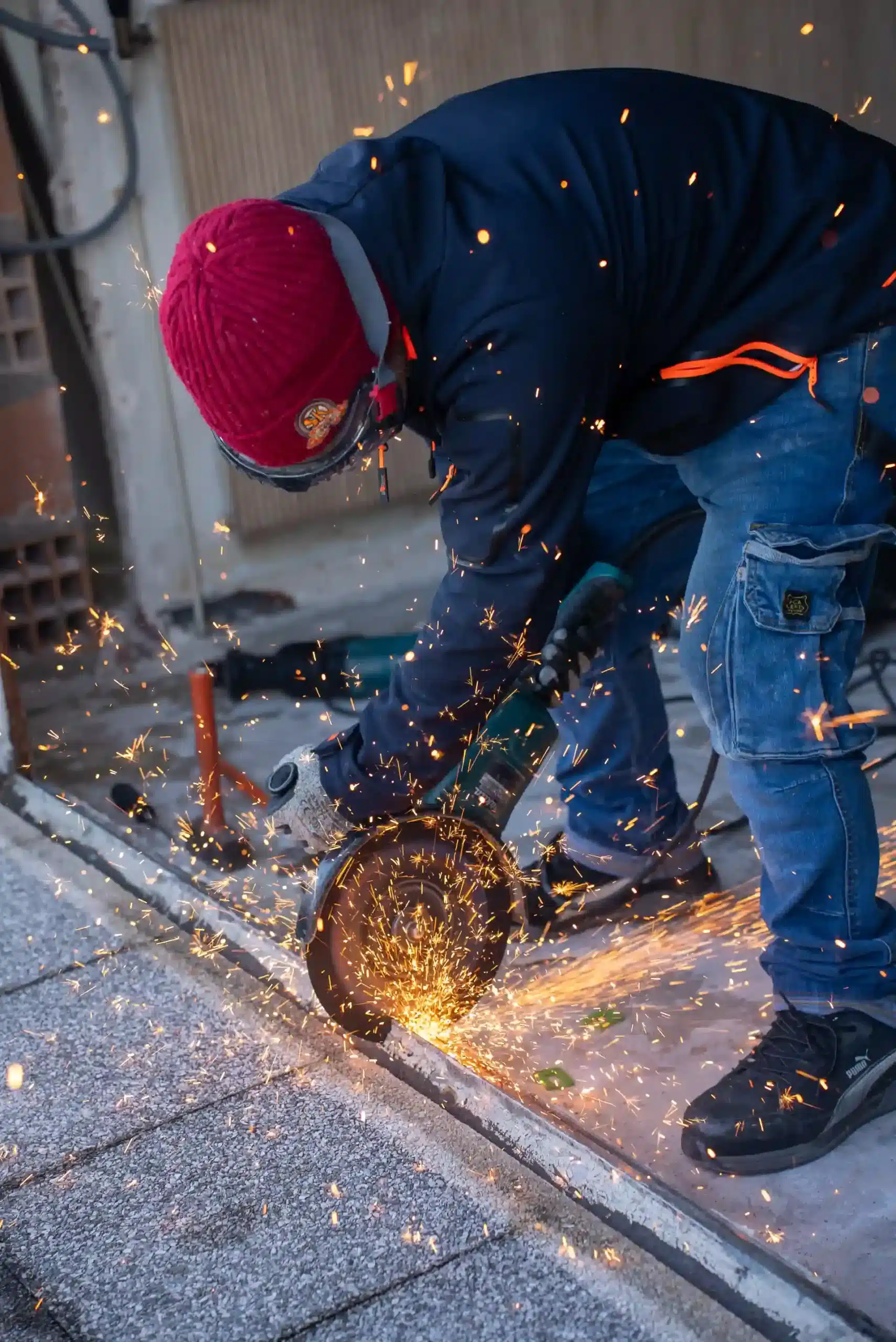Artisan découpant un seuil de porte à la meuleuse sur un chantier extérieur