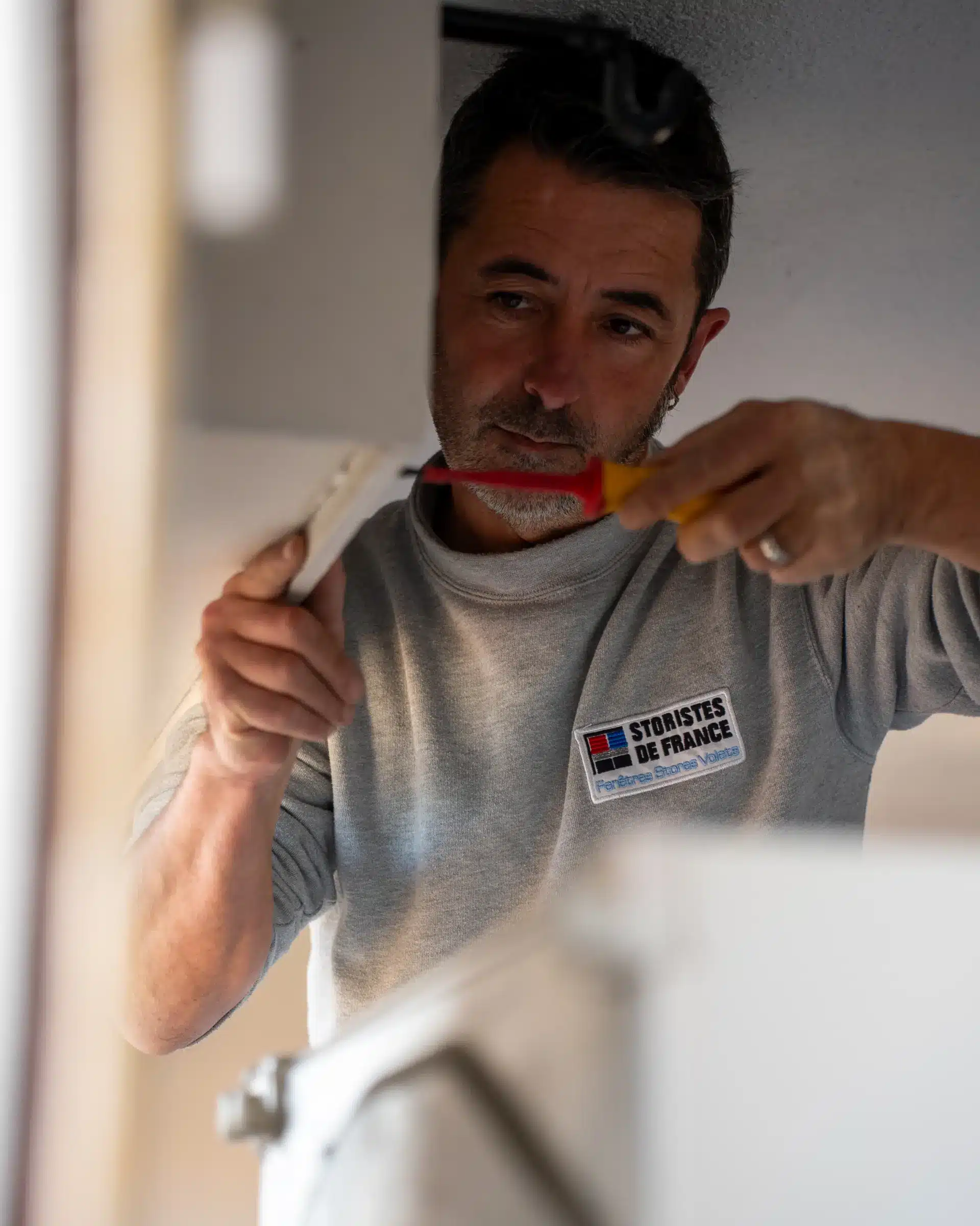 Technicien Adour PVC ajustant un mécanisme de fenêtre avec un tournevis dans un appartement
